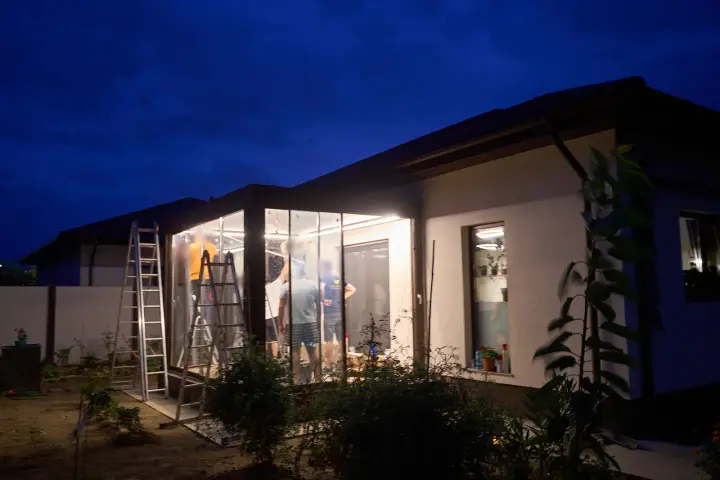 The glass-enclosed terrace lit in the evening at handover