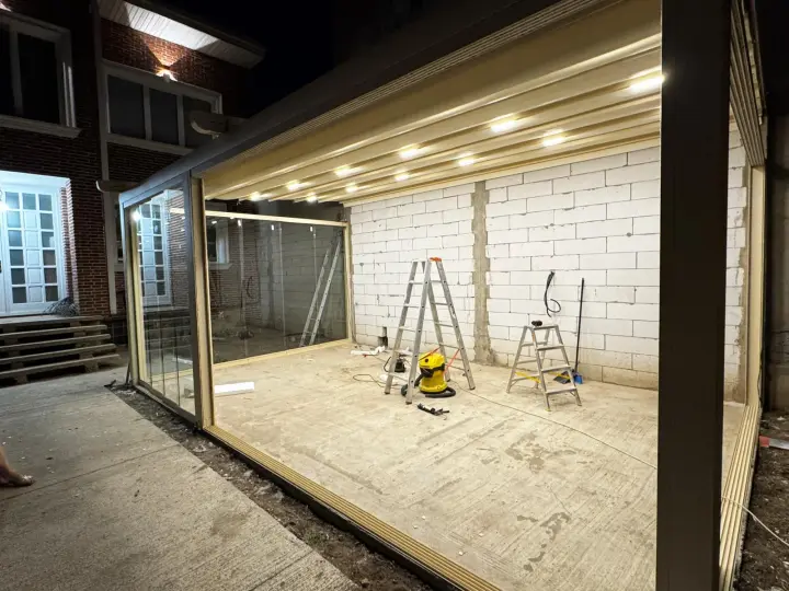 Wave retractable pergola with LED spotlights on and glass enclosure, in the evening