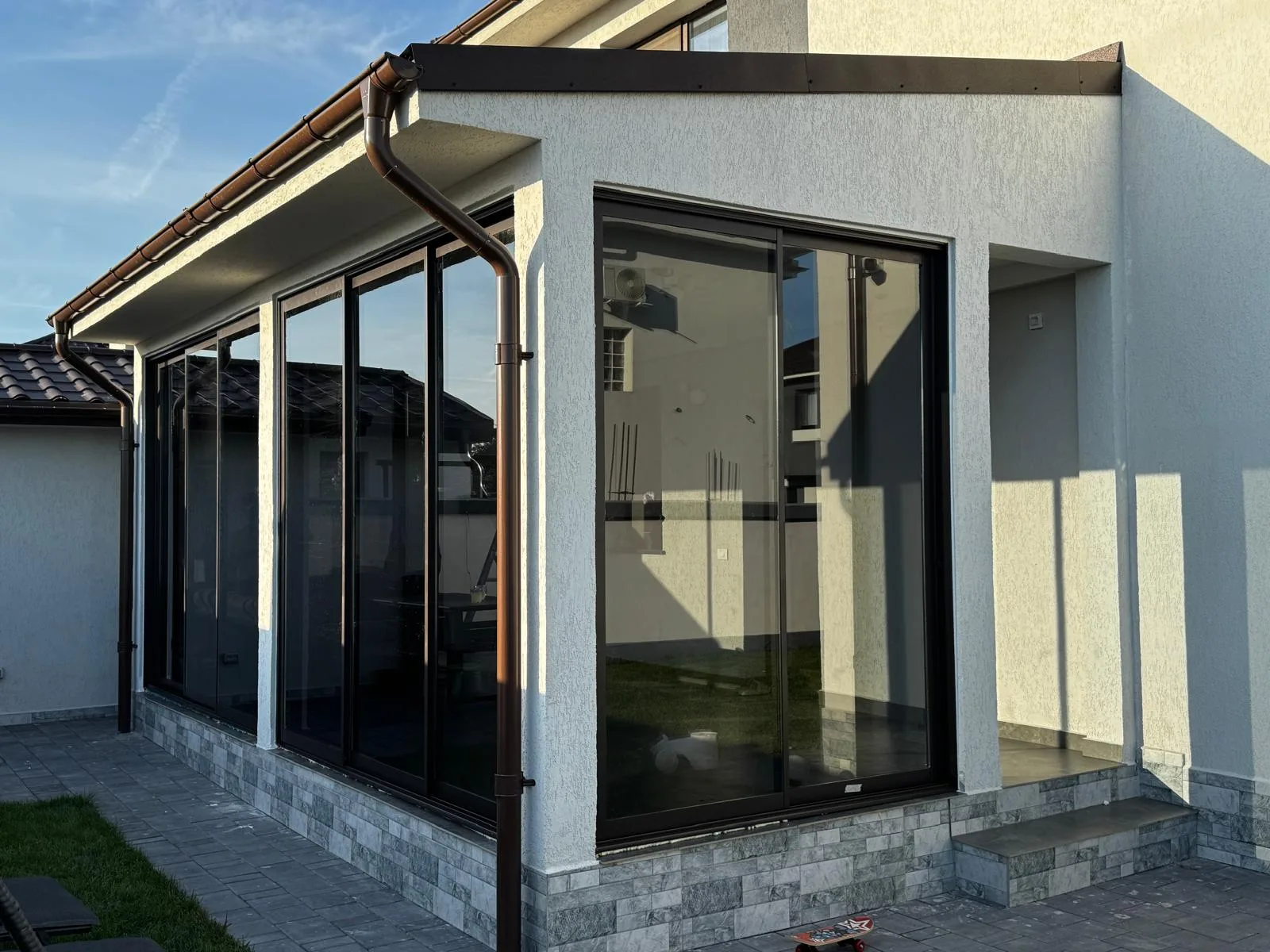 Covered terrace enclosed with sliding glass panels and brown frames