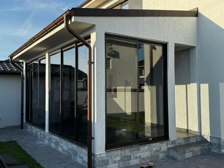 Covered terrace enclosed with sliding glass panels and brown frames