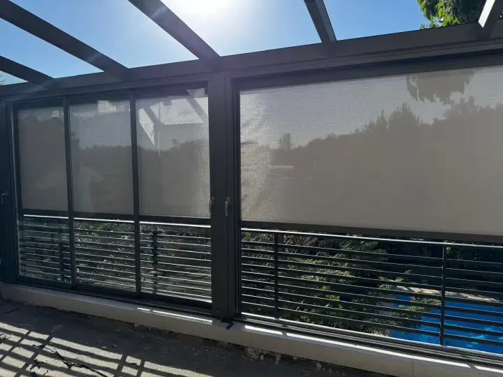 Sliding glass panels and a zip screen along the side of the terrace